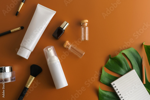 White cosmetic products and green leaves on brown color background. Natural beauty product for branding mock-up concept.
