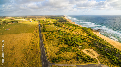 Scenic aerial panorama of ocean coastline and straight rural highway in Australia photo