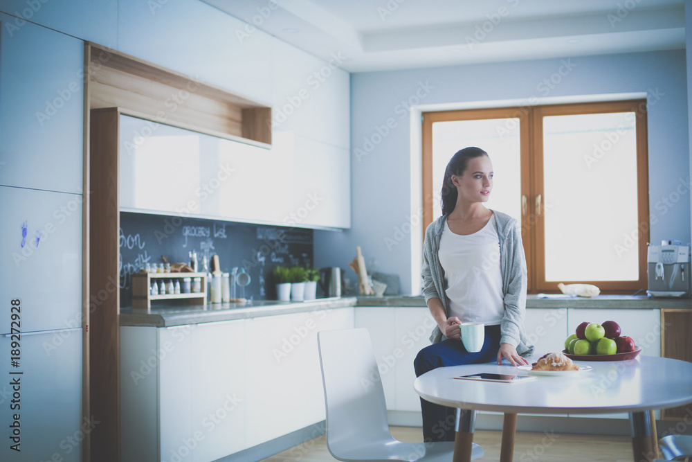 Happy woman drinking tea in the kitchen at home.