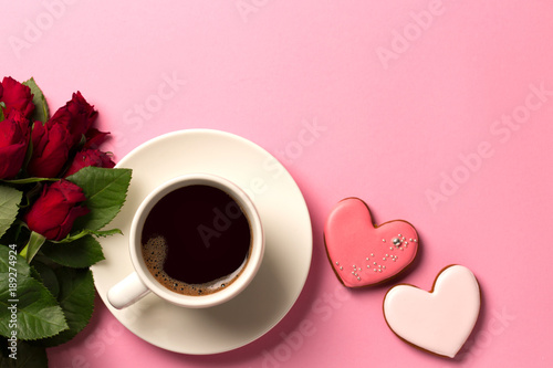 Gingerbread hearts, red roses and a cup of coffee on a pink background.