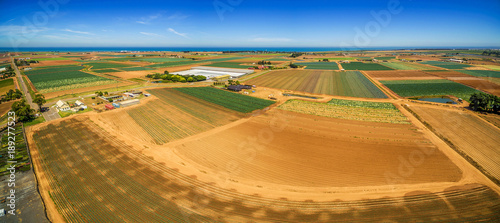 Aerial panorama of plowed fields and crops near ocean coastline on bright summer day. Werribee South, Victoria, Australia photo