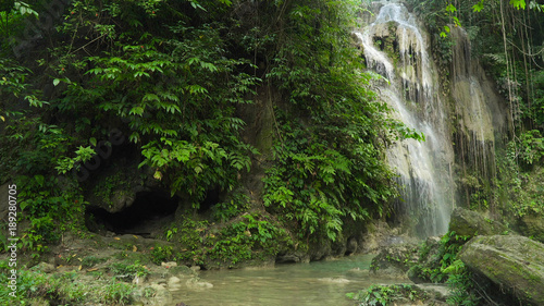 Waterfall in green forest in jungle. Beautiful waterfall in the mountains. Tropical rain forest with waterfall. Philippines  Cebu. Travel concept.