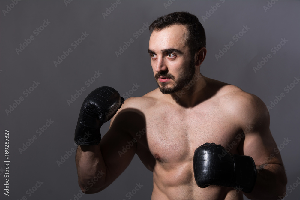 Portrait of a young muscular man in boxing gloves in a pose