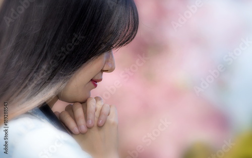 Horizontal view of young beautyful woman is in praying with soft pink color background