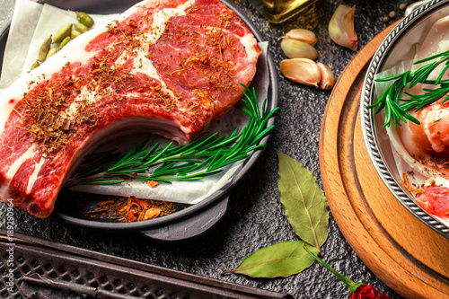 Raw meat on the kitchen table on a metallic background in a composition with cooking accessories photo