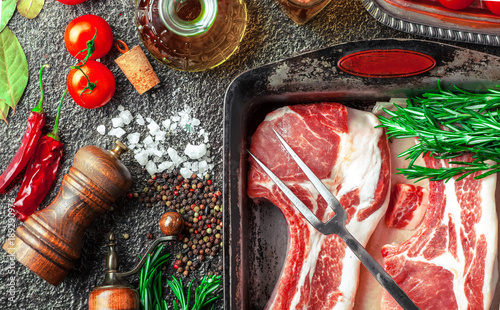 Raw meat on the kitchen table on a metallic background in a composition with cooking accessories photo