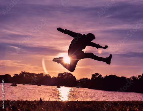 One man is jumping in the air, he is very happy in life with sunset as background.Silhouette image