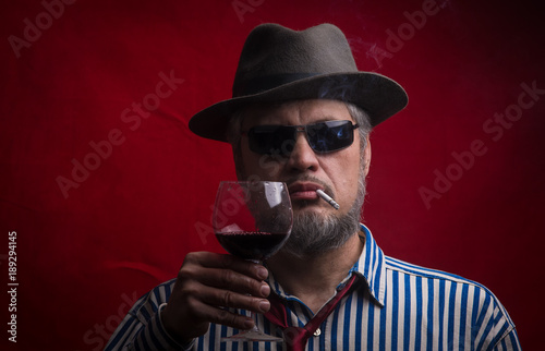 a dark portrait of a bearded man with a glass of wine