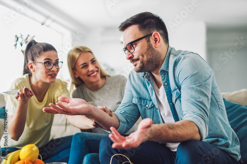 Two women and a man in a living room holding a credit card photo