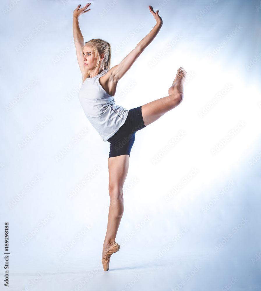 Beautiful female fitness model doing stretches and dancing in a studio, isolated against white background Beautiful female fitness model doing stretches and dancing in a studio, isolated against white background
