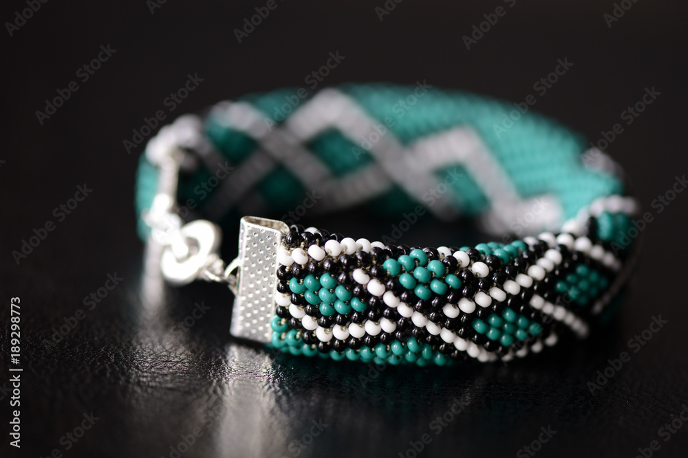 Green bead crochet bracelet with celtic print on a dark background close up Green bead crochet bracelet with celtic print on a dark background close up