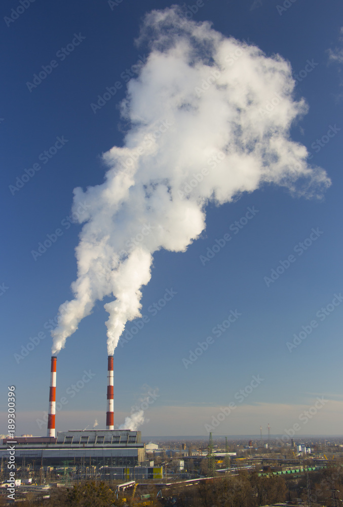 Smoke from industrial chimneys against the blue sky. Pollution.