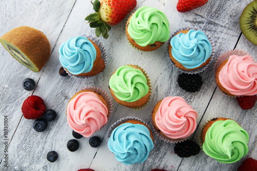 Tasty cupcakes on wooden background. Birthday cupcake in rainbow colors