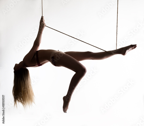 Perfect slim girl with a rope posing on a light background. Sexy athletic body photo