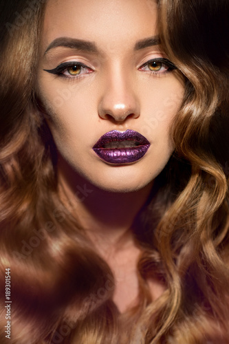 Close up portrait of beautiful girl with perfect curly hairstyle and makeup with magenta gloss lips looking at the camera