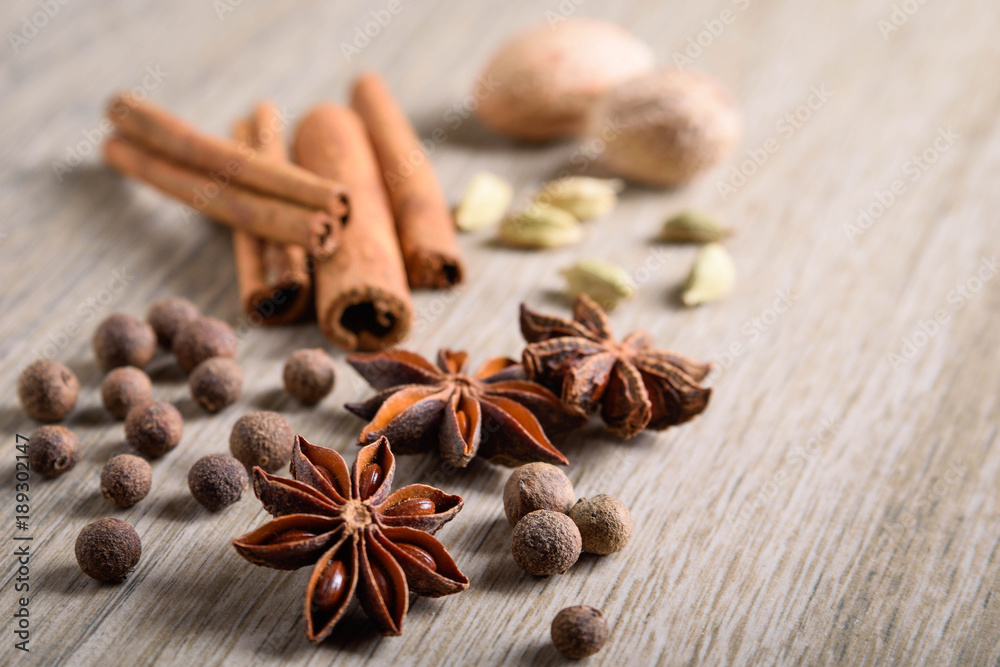 Various Spices background. Cinnamon sticks and anise stars close-up on wood background Various Spices background. Cinnamon sticks and anise stars close-up on wood background