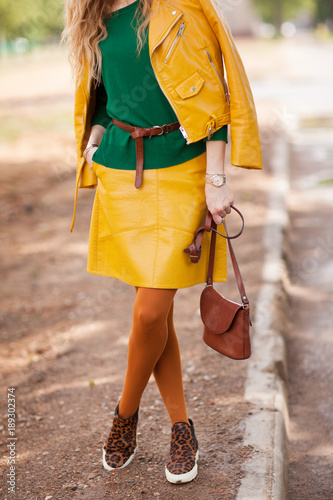 Street, sunny and bright style, a young girl in a leather jacket and a yellow skirt, details, side view.