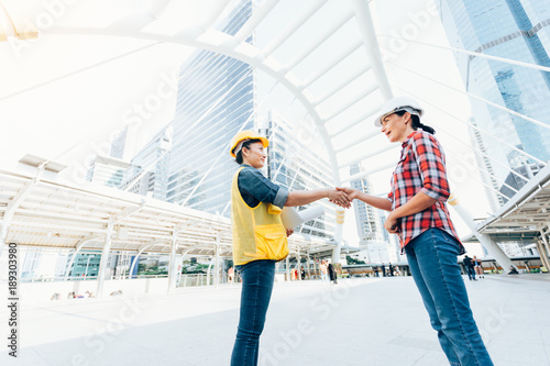 Engineers two woman shaking hands working on plan building construction in city