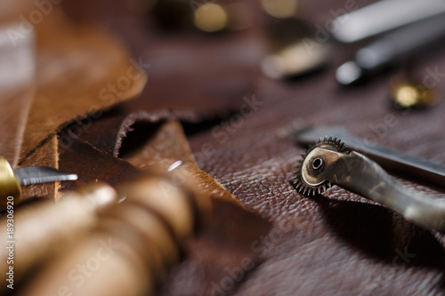 Pieces of natural cow leather and working tools in the tailoring workshop. Close-up