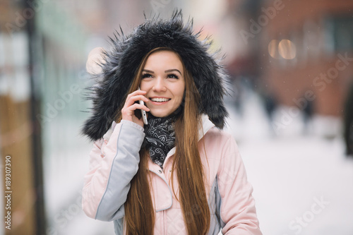 Young woman using smart phone mobile device at winter snowy day