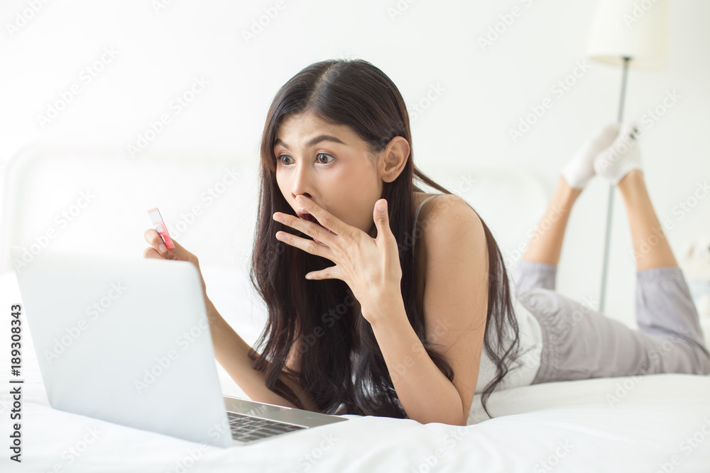 Asian woman looking to laptop with excited emotion. Woman holding craditcard for online shopping. Asian woman looking to laptop with excited emotion. Woman holding craditcard for online shopping.