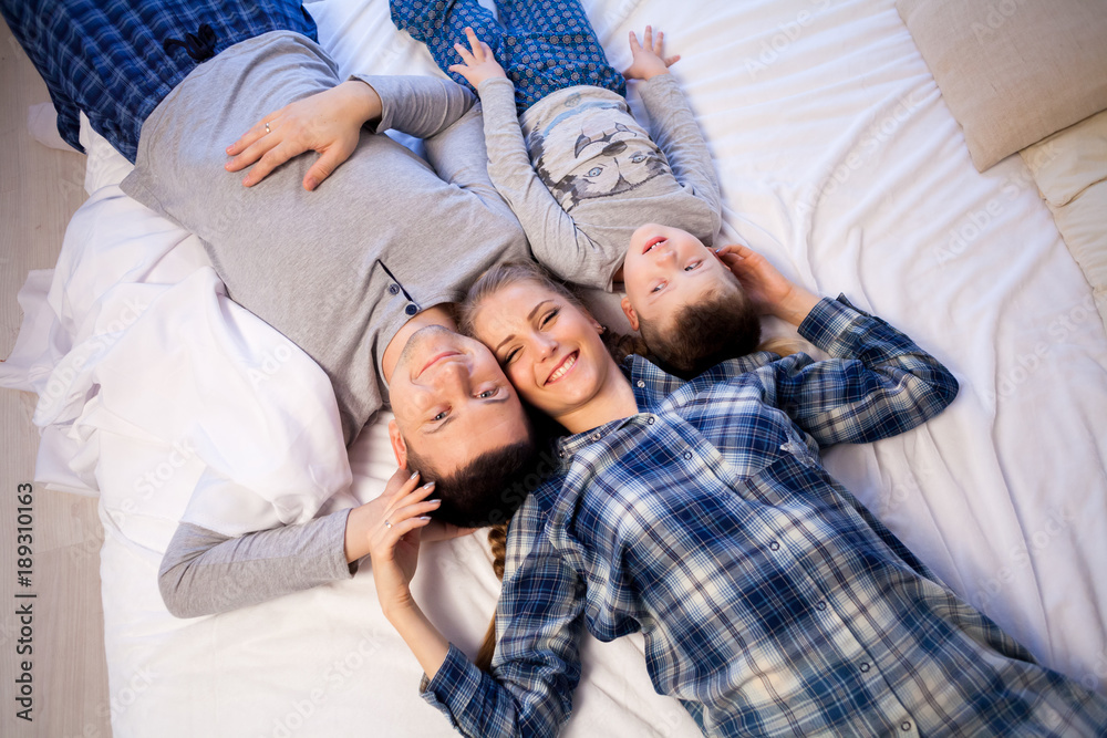 mom dad and son lie on the bed at home dream