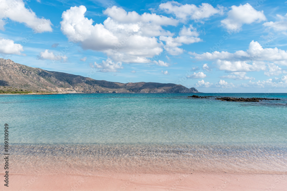 Obraz premium Soft waves of the sea on the pink sand and beautiful beach with cliffs.Coast of Crete island in Greece. Pink sand beach of famous Elafonisi