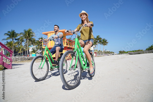 Couple of tourists riding bike in Miami beach