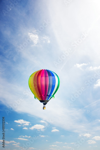 Colorful hot-air balloon riding across blue sky