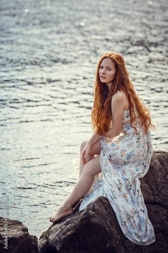 Young red-haired girl in the style of Boho. Enjoys the beauty of the sea coast. The idea and concept of freedom and hippies © selenit