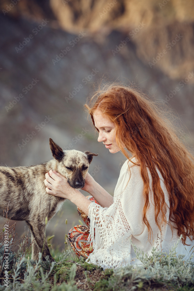 A young girl in a boho style, on the coast with her dog. The idea and concept of freedom and hippies A young girl in a boho style, on the coast with her dog. The idea and concept of freedom and hippies