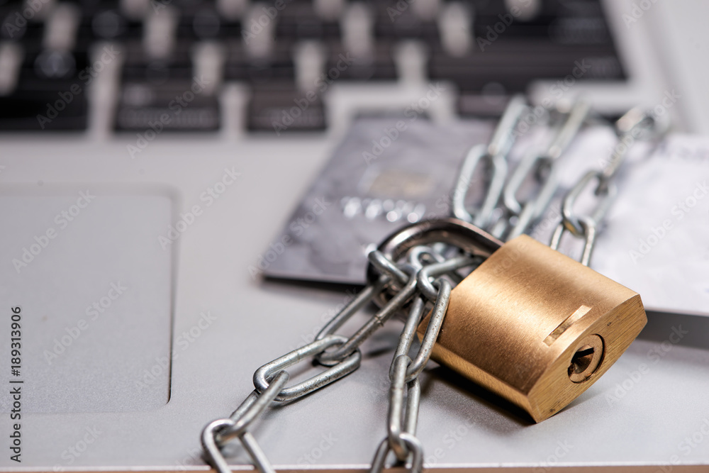 Heavy chain with a padlock around a laptop and credit card on table. Heavy chain with a padlock around a laptop and credit card on table.