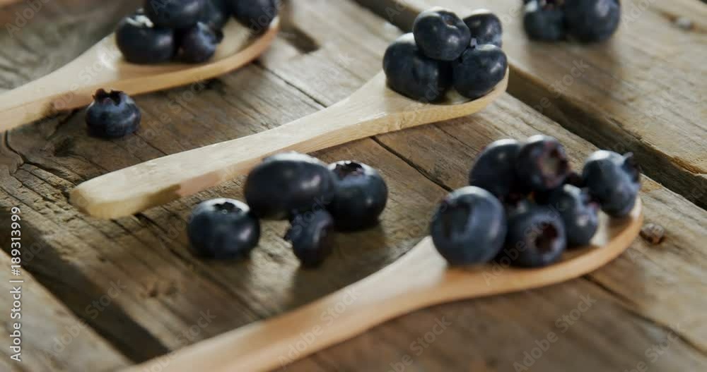 Spoons of blueberries arranged on wooden table Spoons of blueberries arranged on wooden table