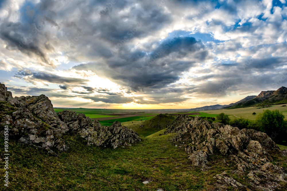 Beautiful landscape with green vegetation, rocks and a blue sunset sky with clouds, Dobrogea, Romania