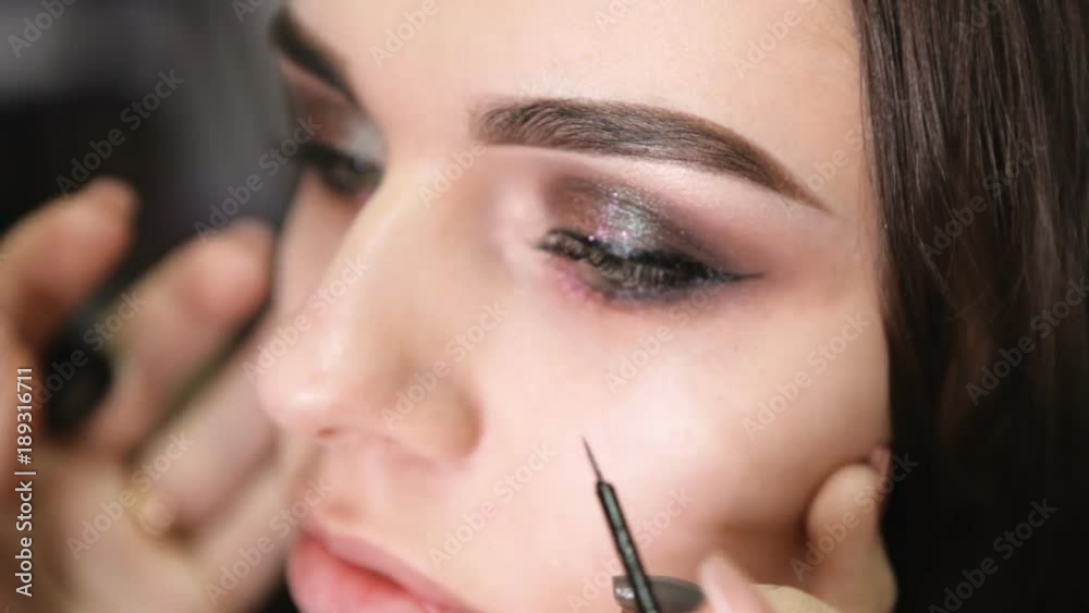 make-up artist draws arrows on the girl's eye make-up artist draws arrows on the girl's eye