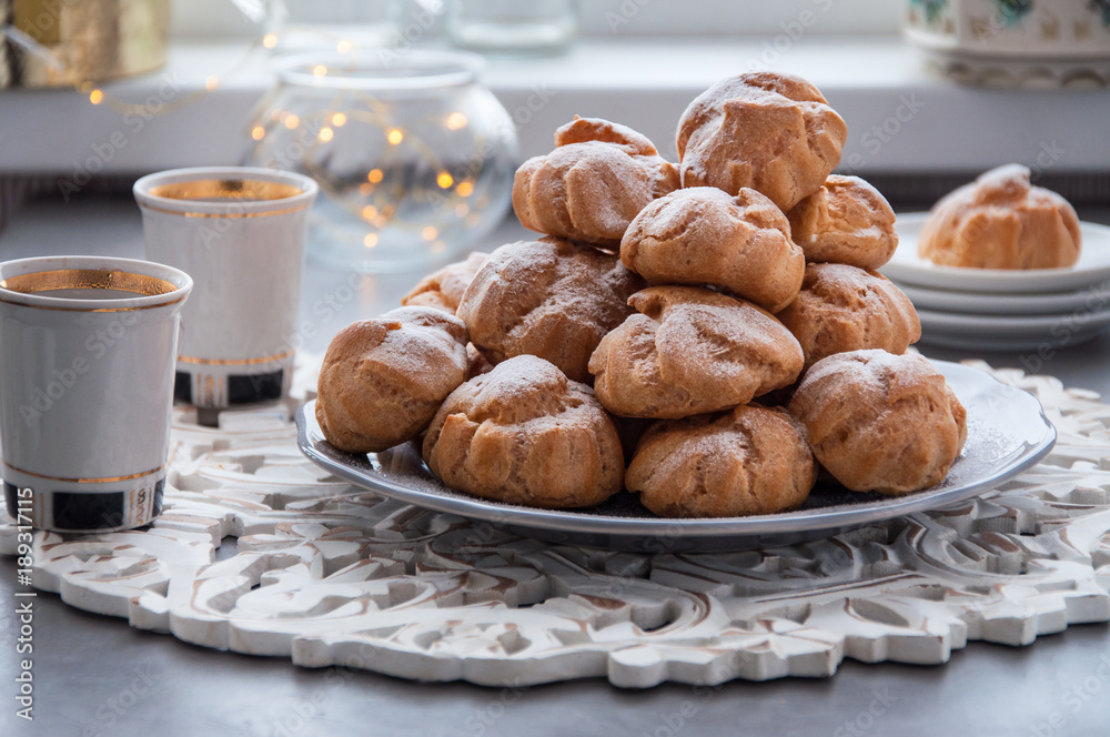 On the table there is a plate of profiteroles, a sweet dessert for breakfast On the table there is a plate of profiteroles, a sweet dessert for breakfast