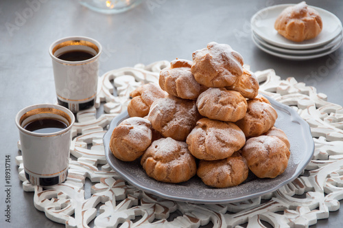 On the table there is a plate of profiteroles, a sweet dessert for breakfast