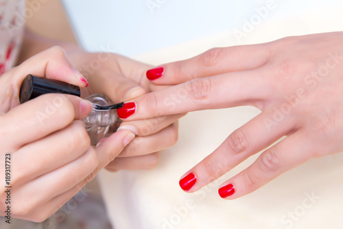woman in a nail salon receiving a manicure by a beautician