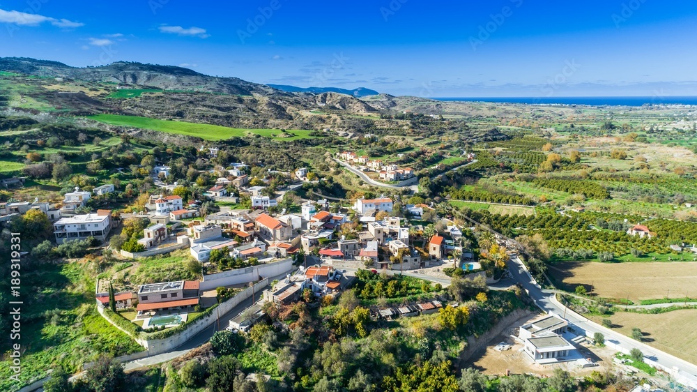 Aerial bird's eye view of Goudi village in Polis Chrysochous valley, Paphos, Cyprus. View of traditional ceramic tile roof houses, church, trees, hills and Akamas - Latchi beach bay from above.