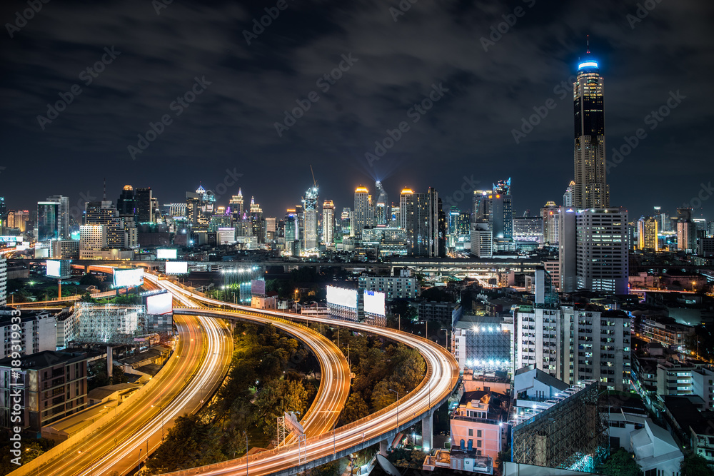 Bangkok City with Curved Express Way and Skyscraper. Top View of City Elevated Highway with Car Traffic Light Trial at Night Time.