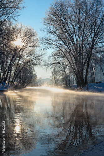 Winter beautiful landscape. Steam rising above the water of the river on a frosty Sunny day.