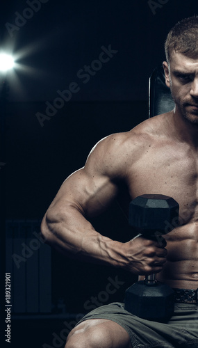 Male bodybuilder, fitness model trains in the gym