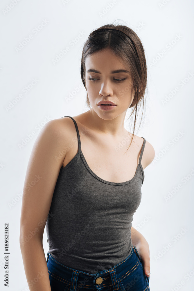 Look away. Nice good looking hopeful woman looking down while wearing shirt and putting hand on the butt Look away. Nice good looking hopeful woman looking down while wearing shirt and putting hand on the butt