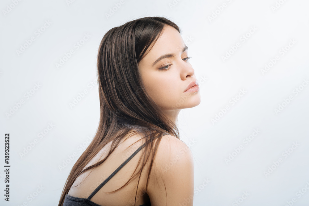 Inspiration in air. Young sweet musing woman posing on the light background while  turning away and looking down