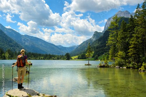 Young hiker woman standing by alpine lake watching mountain landscape. Hintersee, Germany