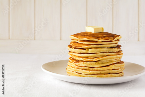 Stack of pancakes with butter and honey on white background