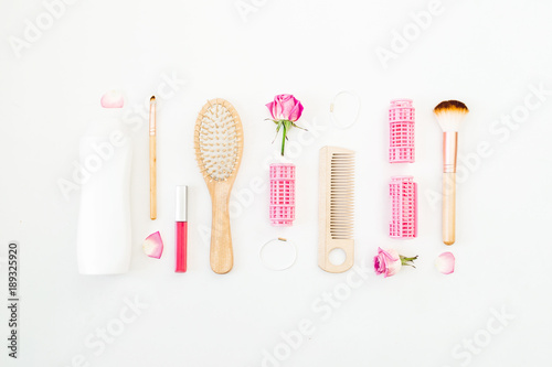 Hair styling concept with tools, curlers and shampoo on white background. Flat lay, top view © artifirsov