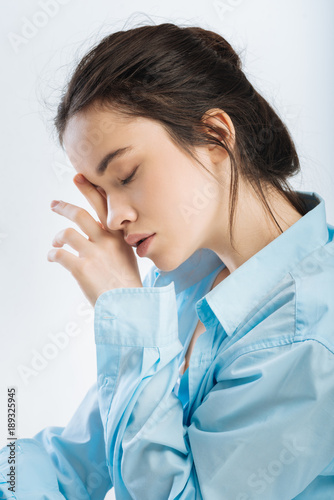 Obligatory nap. Melancholy attractive young woman rubbing her eye while posing in profile and needs to sleep 