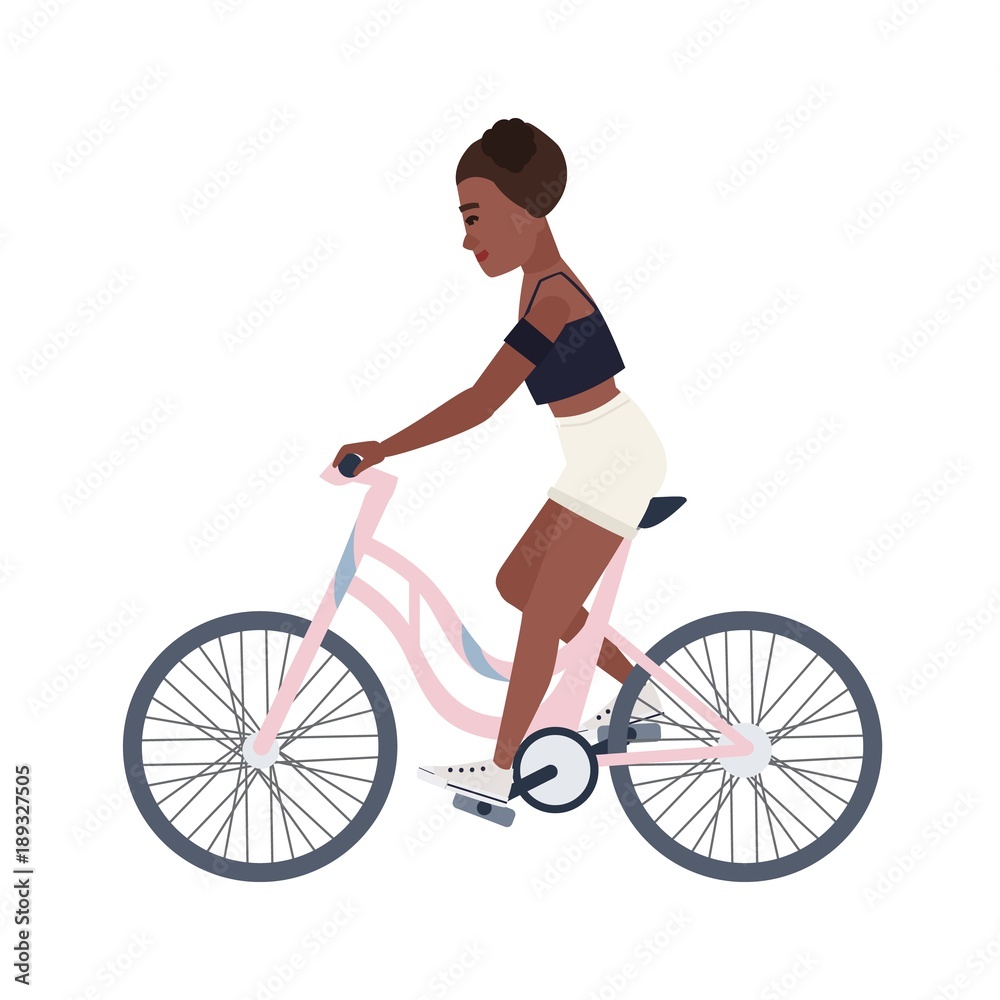 Cute smiling teenage girl dressed in shorts and top riding bicycle