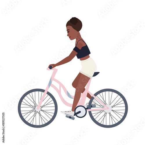 Cute smiling teenage girl dressed in shorts and top riding bicycle